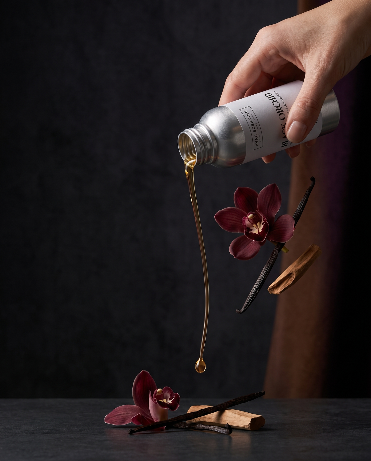 A hand pours a viscous golden amber liquid from a silver bottle labeled &