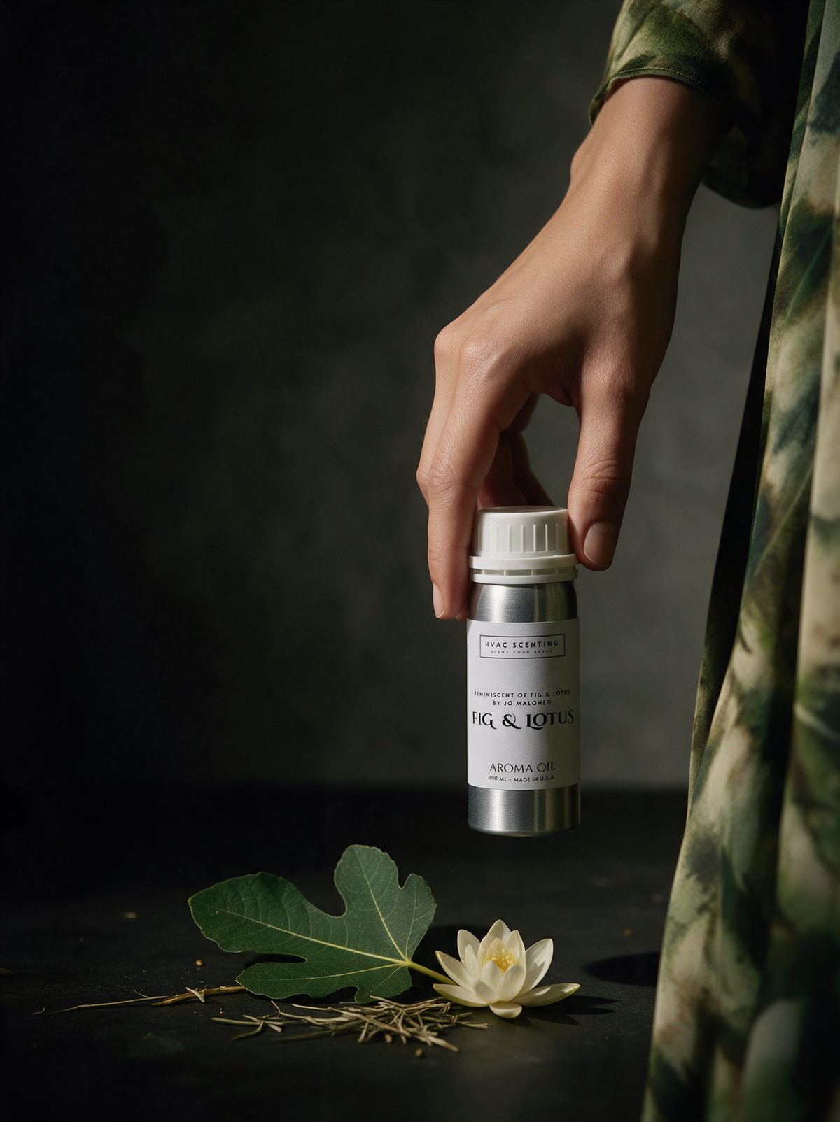 A hand wearing a green and beige patterned robe holds a small silver bottle labeled 'DR. & L.